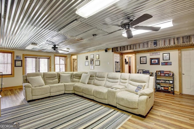 living area featuring visible vents, baseboards, light wood-style floors, and ceiling fan