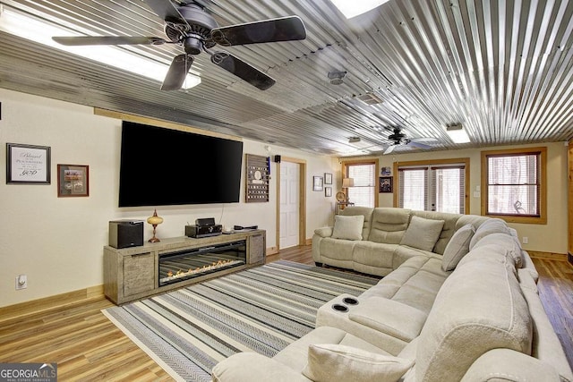 living area with baseboards, a ceiling fan, and light wood-style floors