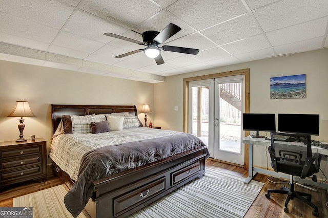 bedroom with access to outside, french doors, light wood-style flooring, and a drop ceiling