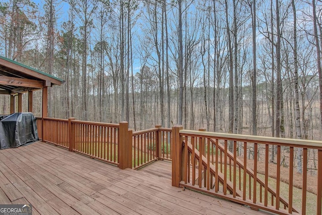 wooden deck with a forest view and a grill