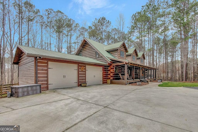 view of property exterior with metal roof, a garage, and driveway