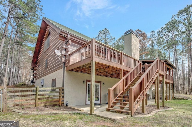 rear view of property featuring fence, stairway, stucco siding, a deck, and a patio area