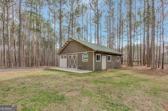 exterior space with an outbuilding, a detached garage, and a front lawn