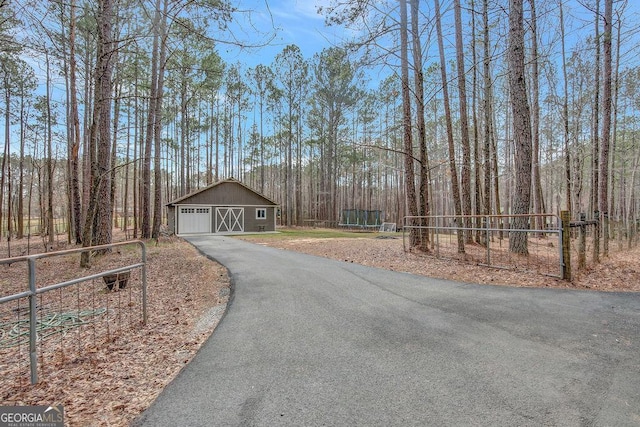 view of road featuring aphalt driveway and a barn