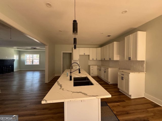 1510 Olympian Way SW, Atlanta, GA 30310 - kitchen featuring a kitchen island with sink, tasteful backsplash, white cabinets, and light stone counters