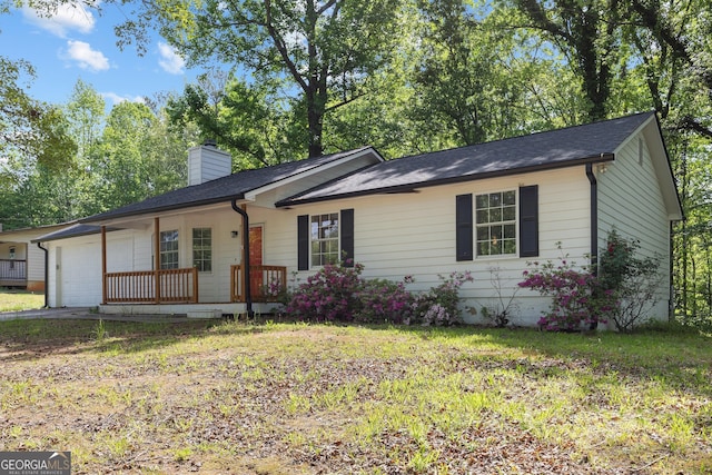 ranch-style house featuring a garage, a front yard, a chimney, and covered porch