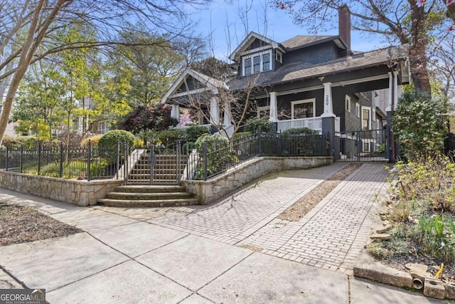 view of front of property with a fenced front yard, a porch, a chimney, and stairs