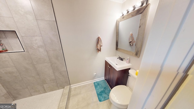 full bath featuring tile patterned floors, toilet, a tile shower, baseboards, and vanity