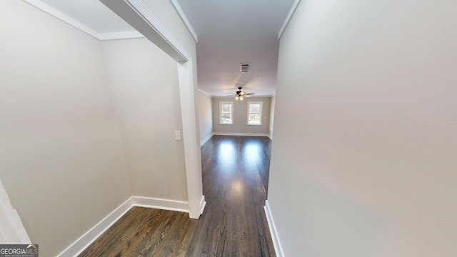 hallway featuring dark wood-style floors, visible vents, baseboards, and ornamental molding