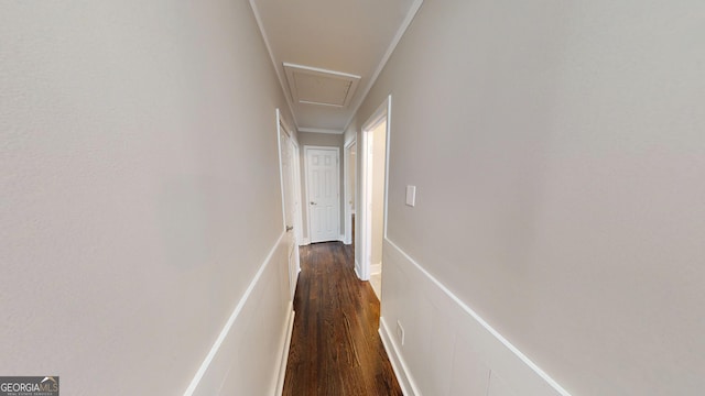 hallway with attic access, ornamental molding, and dark wood-style flooring