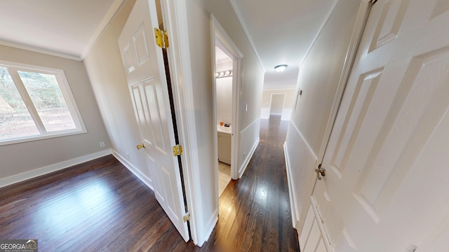 hallway with dark wood-type flooring, baseboards, and ornamental molding