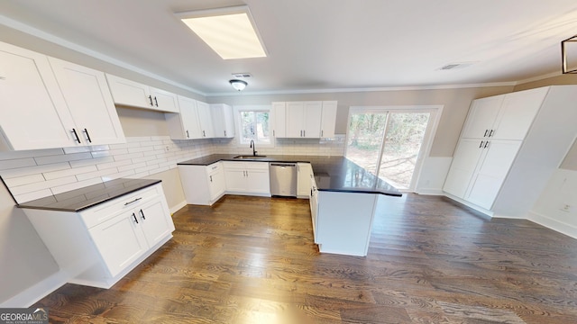 kitchen with a sink, dark countertops, a peninsula, white cabinets, and dishwasher