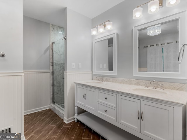 1300 Lakehaven Pkwy, Mcdonough, GA 30253 - bathroom with a shower stall, wood tiled floors, double vanity, wainscoting, and a chandelier