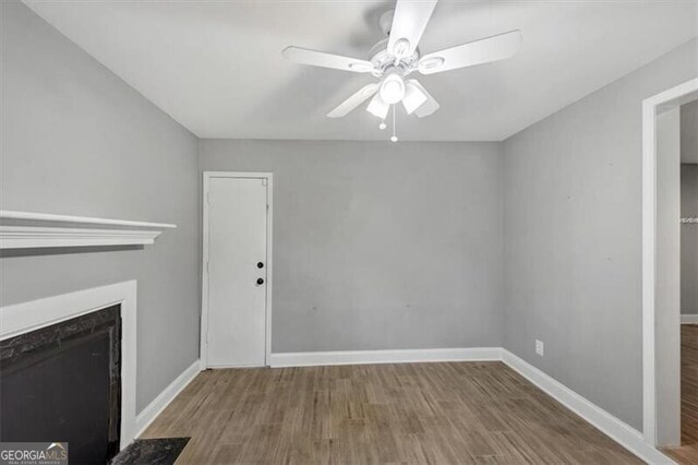 117 Lablanc Way NW, Atlanta, GA 30327 - unfurnished living room with baseboards, wood finished floors, ceiling fan, and a high end fireplace