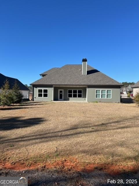 back of house featuring a chimney and a shingled roof