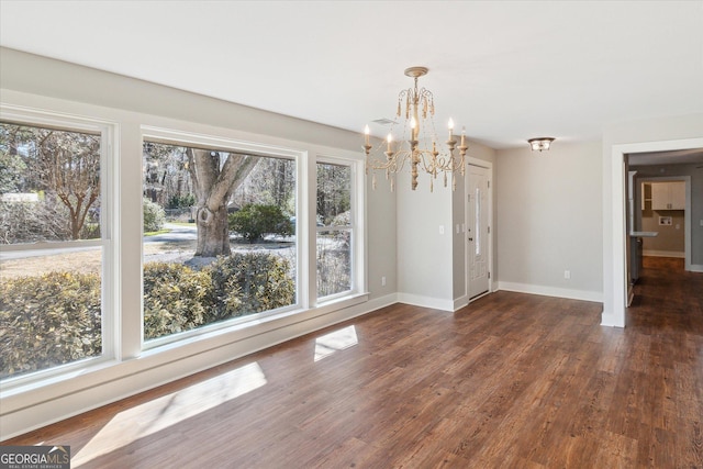 unfurnished dining area with an inviting chandelier, wood finished floors, and baseboards