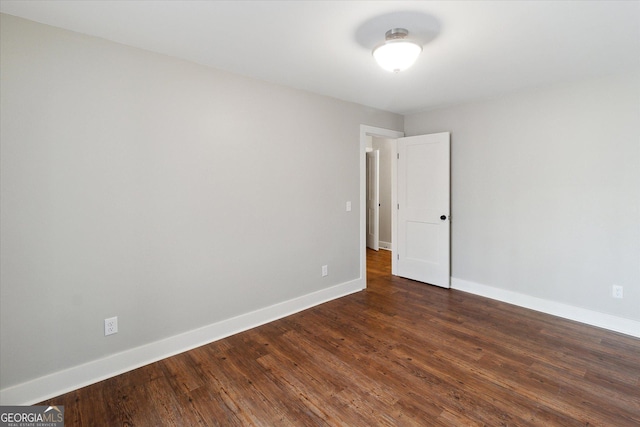 spare room featuring baseboards and dark wood-style flooring
