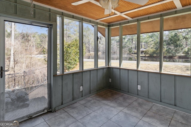 unfurnished sunroom featuring a water view and a ceiling fan