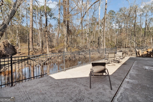 view of patio featuring a water view and fence