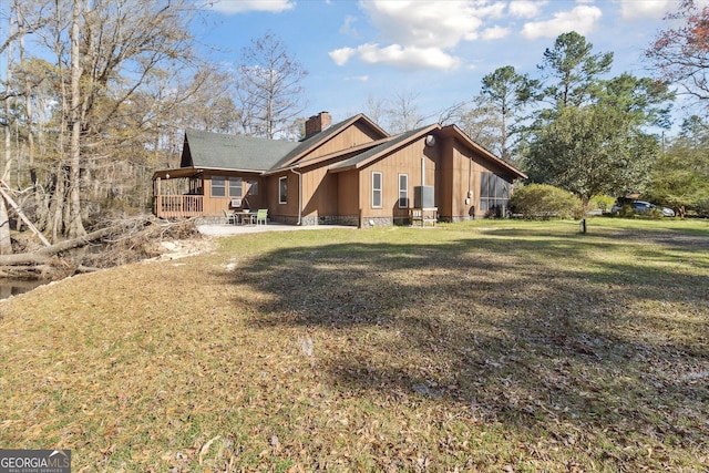 view of side of property with a chimney, a patio area, board and batten siding, and a lawn