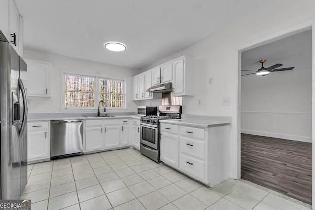4304 Ruth Ln, Powder Springs, GA 30127 - kitchen with white cabinets, appliances with stainless steel finishes, under cabinet range hood, a sink, and light tile patterned floors