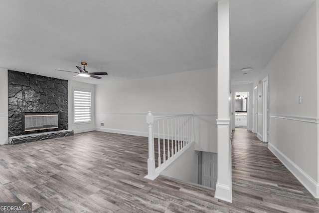 4304 Ruth Ln, Powder Springs, GA 30127 - unfurnished living room with a stone fireplace, baseboards, wood finished floors, and a ceiling fan