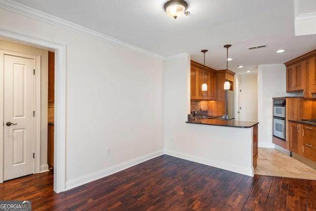 kitchen with visible vents, a sink, appliances with stainless steel finishes, dark countertops, and brown cabinets