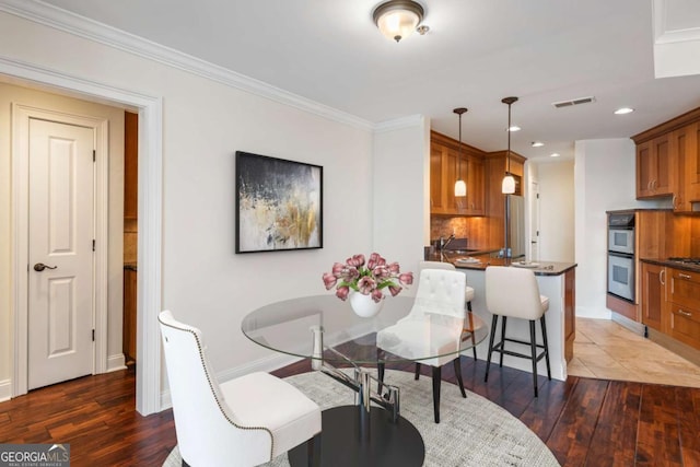 dining space with visible vents, crown molding, baseboards, and wood-type flooring