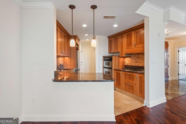 kitchen with dark stone countertops, visible vents, stainless steel appliances, decorative backsplash, and brown cabinets