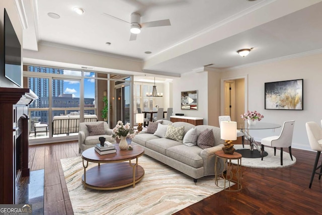 living room with baseboards, a fireplace, ornamental molding, wood-type flooring, and ceiling fan with notable chandelier