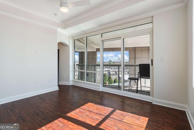 empty room with baseboards, arched walkways, hardwood / wood-style floors, and a ceiling fan