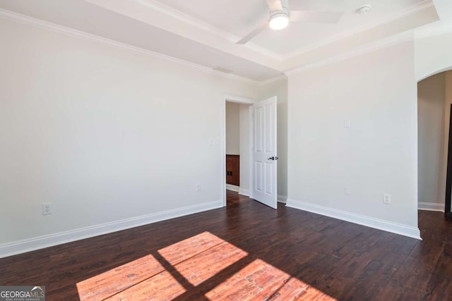 spare room featuring baseboards, arched walkways, dark wood-style flooring, and ornamental molding