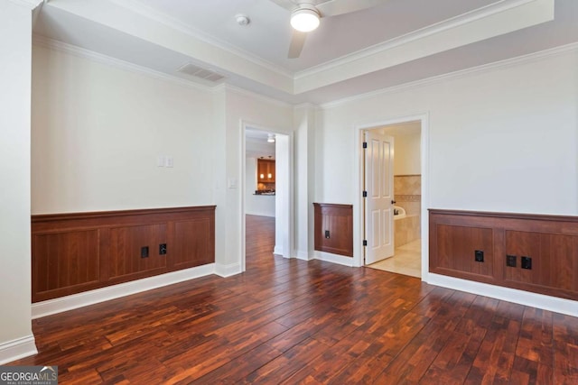 empty room with visible vents, a raised ceiling, ceiling fan, and wood-type flooring