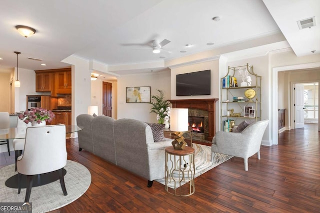 living area with visible vents, baseboards, a premium fireplace, hardwood / wood-style flooring, and a ceiling fan