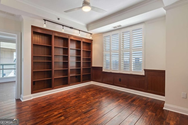 empty room featuring dark wood-type flooring, a wainscoted wall, and ornamental molding