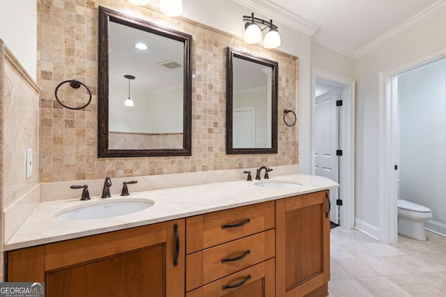 bathroom featuring a sink, toilet, double vanity, and crown molding