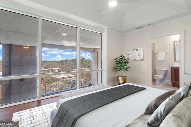 bedroom featuring connected bathroom, wood finished floors, visible vents, and baseboards