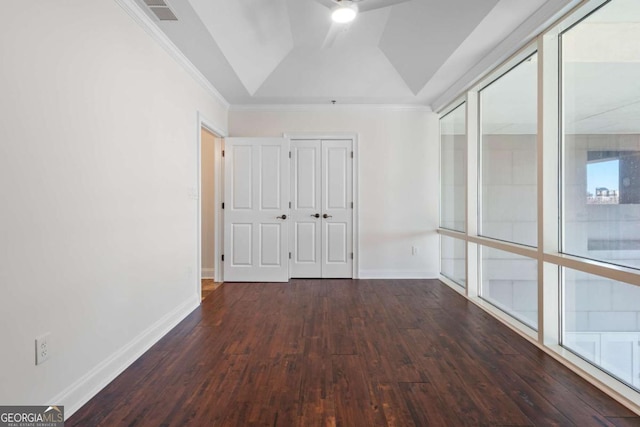 unfurnished bedroom with a tray ceiling, visible vents, wood-type flooring, and baseboards