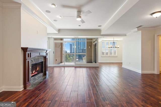 living area featuring ornamental molding, ceiling fan with notable chandelier, dark wood-style floors, a fireplace, and baseboards