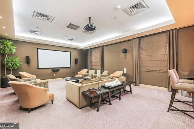 home theater with a raised ceiling, light colored carpet, and visible vents