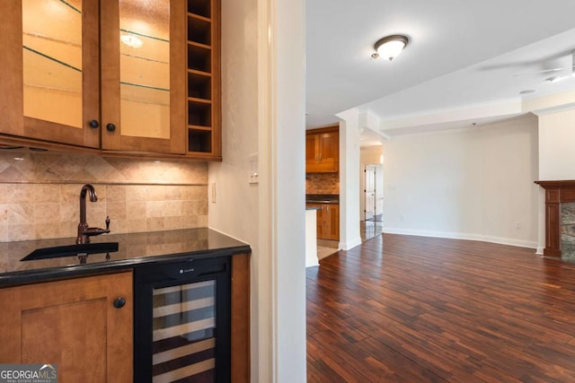 bar featuring dark wood-style floors, beverage cooler, a sink, indoor wet bar, and decorative backsplash