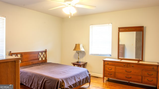 bedroom with ceiling fan, visible vents, baseboards, and wood finished floors