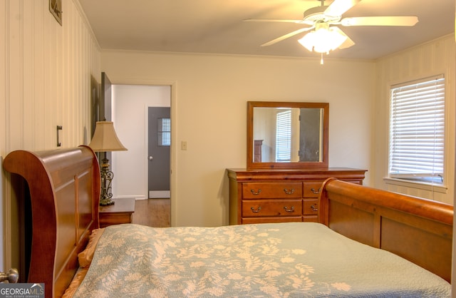 bedroom with crown molding, ceiling fan, and wood finished floors