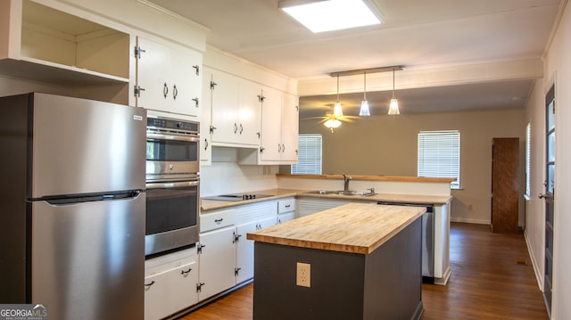 kitchen with wooden counters, a peninsula, a sink, stainless steel appliances, and white cabinetry