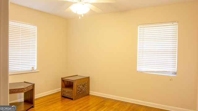 spare room featuring baseboards, light wood-type flooring, and a ceiling fan