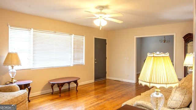 living area with wood finished floors, baseboards, a wealth of natural light, and ceiling fan