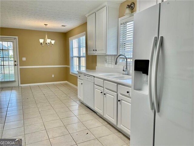 2703 Regal Cir, Conyers, GA 30012 - kitchen with white appliances, light tile patterned floors, a chandelier, light countertops, and white cabinets