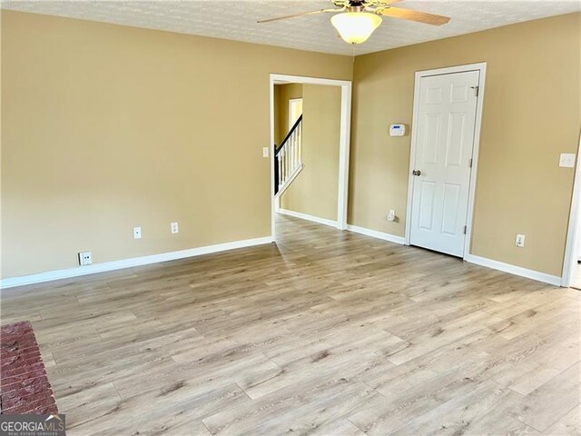 2703 Regal Cir, Conyers, GA 30012 - unfurnished room with a ceiling fan, light wood finished floors, a textured ceiling, and stairway