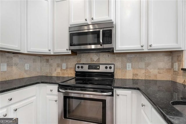 kitchen with white cabinets, dark stone counters, backsplash, and appliances with stainless steel finishes