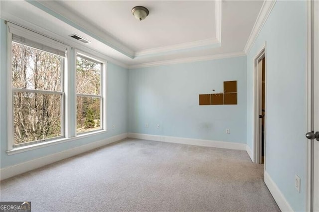 carpeted empty room featuring a tray ceiling, visible vents, baseboards, and ornamental molding